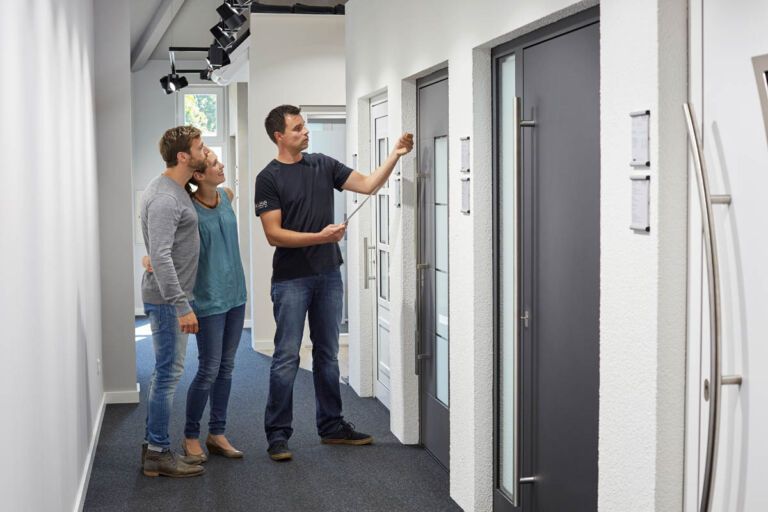 Roland Kruse berät zwei Kunden aus Arnsberg tu Türen in der Ausstellung von Kruse Türen und Böden aus Brilon. Die Kunden gucken sich gerade eine Haustür an.