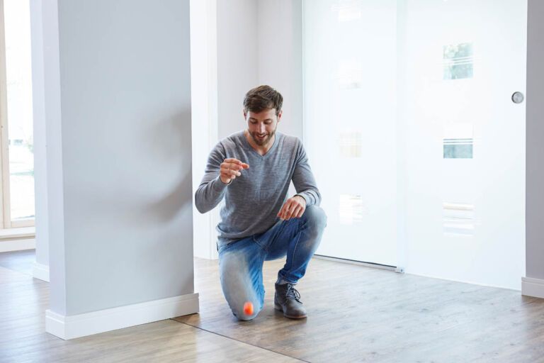 Ein Mann macht in der Ausstellung von Kruse Türen und Böden den Golfballtest. In der Ausstellung können Kunden aus Arnsberg, Paderborn und Umgebung Bodenbeläge testen.