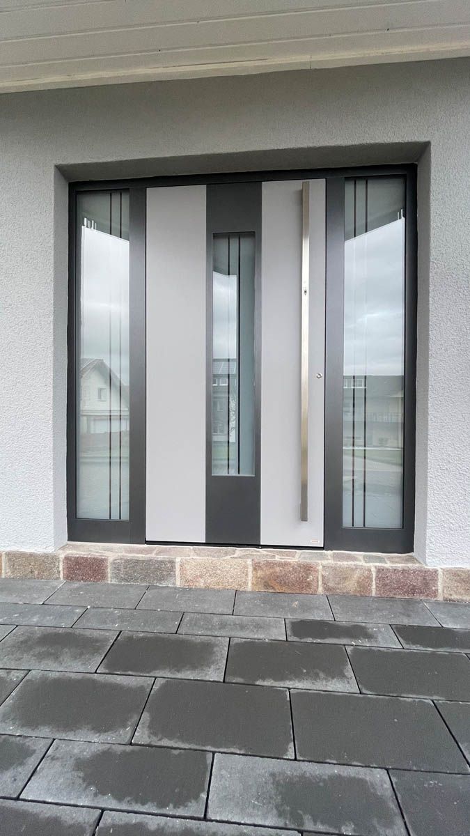 Auf dem Bild sieht man eine schöne graue Haustür in Brilon. Die Haustür hat drei eingesetzte Glaselemente, die durch ihre Milchgläser guten Lichteinfall bieten. Kruse Türen und Böden ist dein Ansprechpartner für Haustüren in Brilon, Arnsberg, Paderborn und Umgebung.